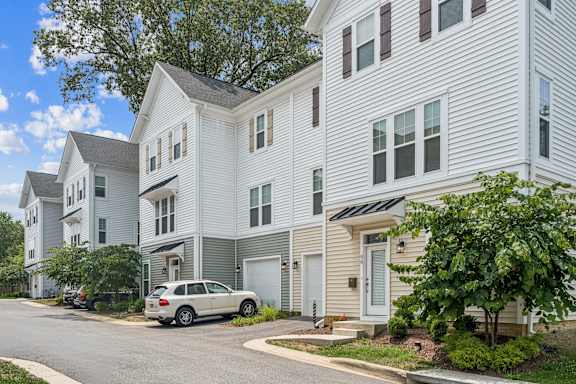 A white car is parked in front of a two-story apartment building.