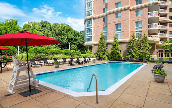 A red umbrella is next to a pool.