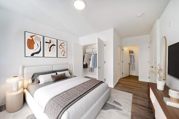 A bedroom with a large bed and a TV on the wall.