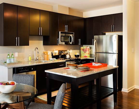 A modern kitchen with a glass table and black cabinets.