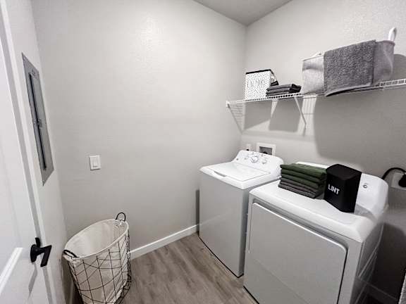 A laundry room with a washer and dryer and a basket on the floor.