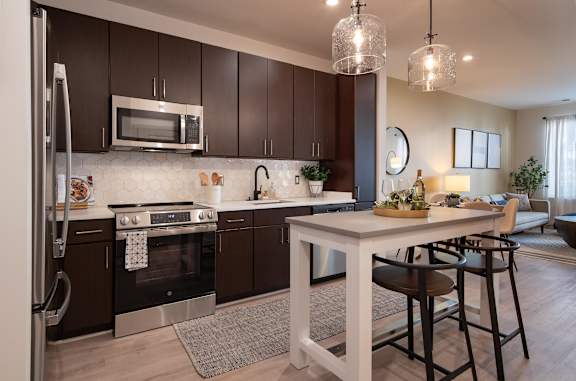 A modern kitchen with dark brown cabinets and stainless steel appliances.