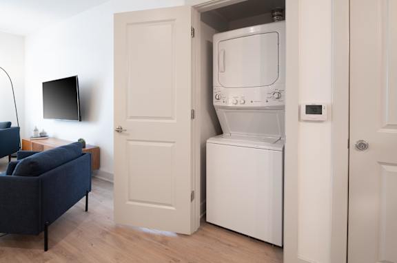 A modern laundry room with a washer and dryer built into the cabinetry.