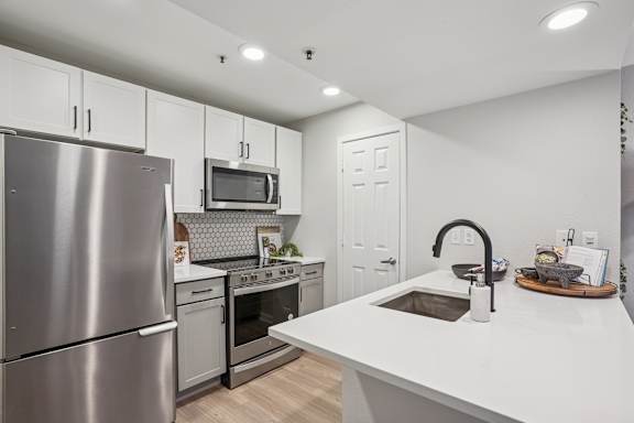 A modern kitchen with stainless steel appliances and white countertops.