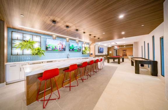 a long bar with red chairs and a pool table in a lobby