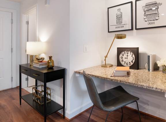 A black desk with a chair and a clock on the wall.