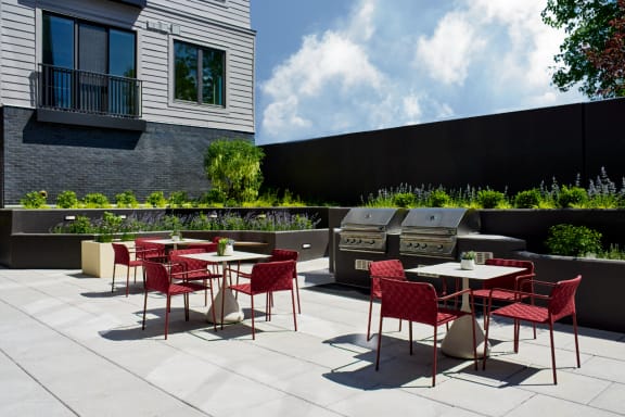 an outdoor patio with tables and chairs and barbecue grills