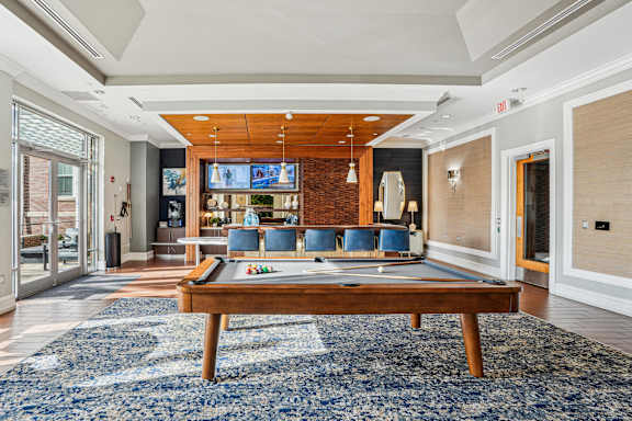 A billiard table is in the middle of a room with a TV and a couch.