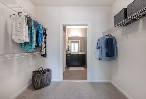a closet with clothes hanging on the wall and a door to a bathroom