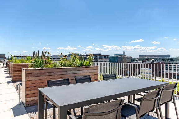a rooftop patio with a table and chairs and a view of the city
