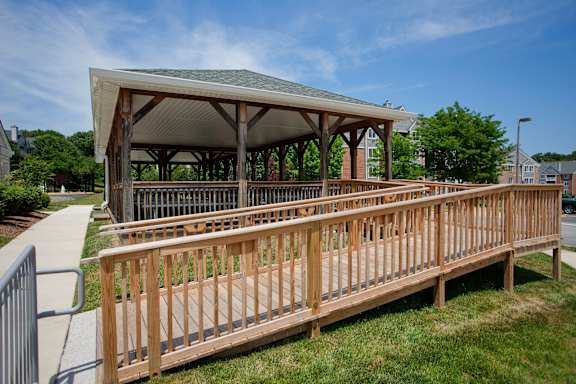 A wooden pavilion with a metal roof is surrounded by a wooden fence.