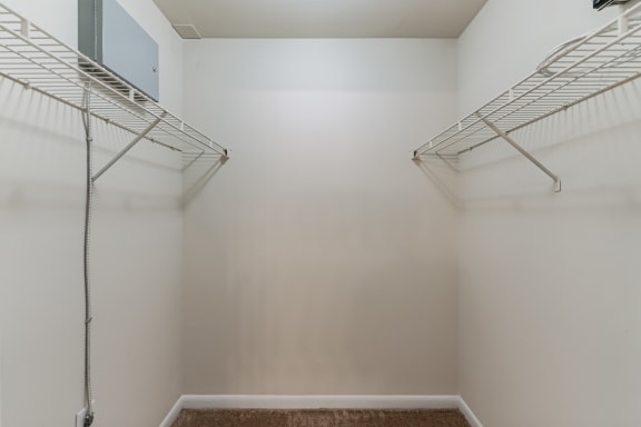 an empty closet with two wire shelves in a white room