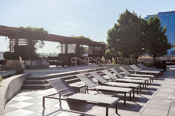 A row of sun loungers are arranged on a concrete platform.