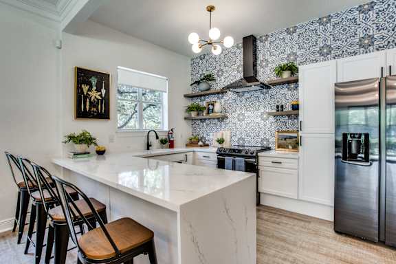 A kitchen with a white marble countertop and a tile backsplash.