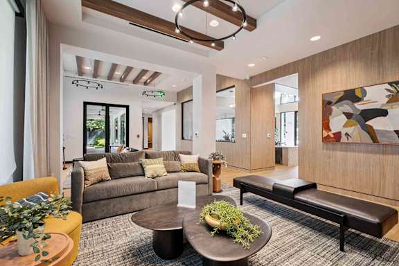 A modern living room with a large couch, a coffee table, and a painting on the wall.