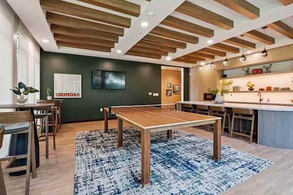 A room with a wooden table and chairs and a blue rug.