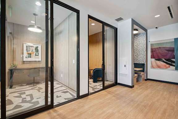 A modern office space with glass walls and wooden floors.
