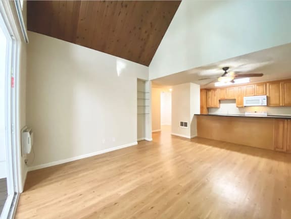 Spacious Living room View with wood flooring and a kitchen at Castlewood Apartments in Walnut Creel, CA