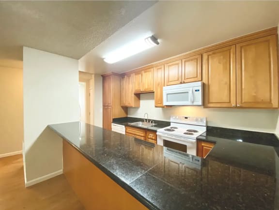 Spacious Kitchen with wooden cabinets and black counter tops at Castlewood Apartments in Walnut Creek, California