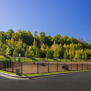 A black fence surrounds a green sign on a street.at 198 Milltown Apartments, Burlington, 27215