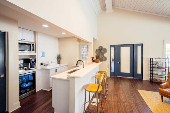 A kitchen with white cabinets and a white island with yellow chairs at Inverness Cliffs Apartments in Birmingham, AL