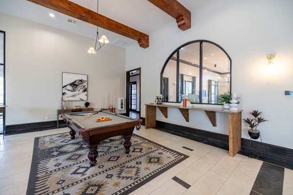 A pool table is in the middle of a room with a mirror and a bench at Pecan Springs, San Antonio, 78249