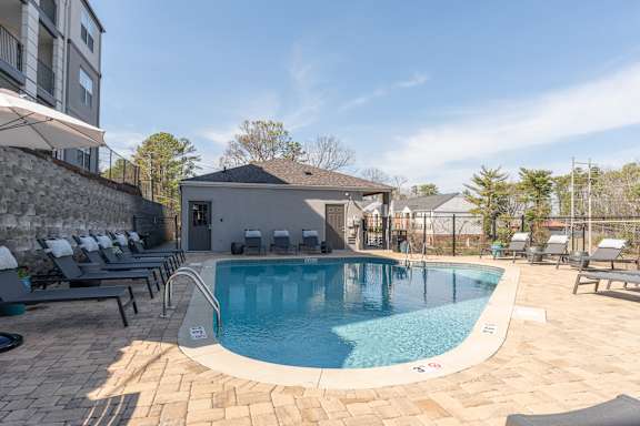 a swimming pool with lounge chairs and a building in the background at WildForest Apartments, Birmingham, AL, 35209