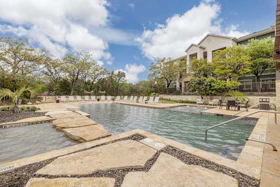 A large outdoor pool surrounded by stone steps at Pecan Springs, San Antonio, Texas