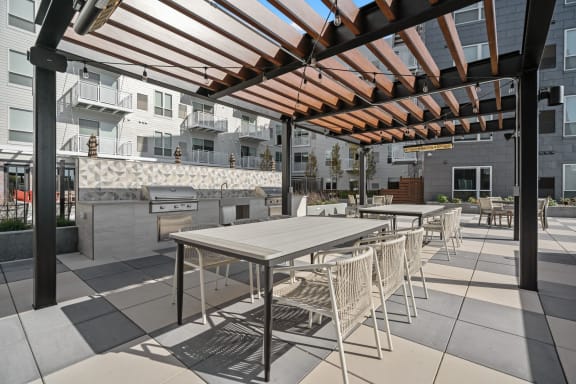a communal patio with tables and chairs and a grill at The Hallon, Minnesota, 55343
