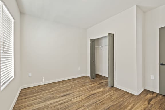 A bedroom with wood floors, white walls, and ample closet space at Azalea, Luxury Tampa Apartments