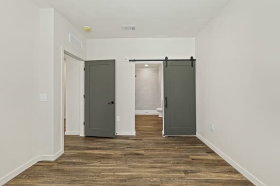 Bedroom with sliding barn door and wood floors at Azalea, Luxury Tampa Apartments