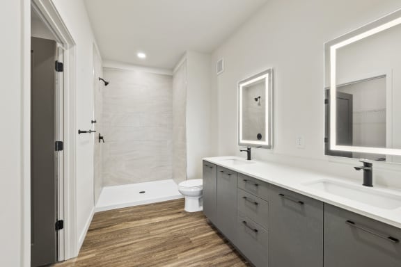 A modern bathroom with wood floors, quartz countertops, and spa shower at Azalea, Luxury Tampa Apartments