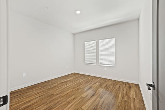 Bedroom with white walls and wood flooring and a window at Azalea Luxury Tampa Apartments