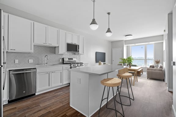 a kitchen with white cabinets and a large island with three stools at The Hallon, Hopkins, MN, 55343