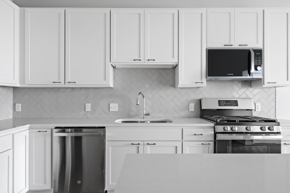 a kitchen with white cabinets and stainless steel appliances at The Hallon, Hopkins, MN