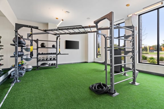 a home gym with green turf and weights equipment and a window