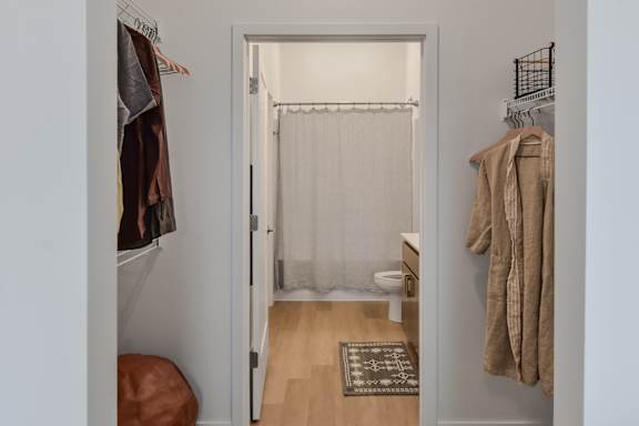 A white door with a curtain and a rug on the floor.