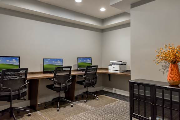 A room with a desk, chairs, and computers.