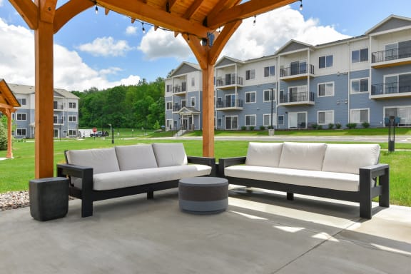 a patio with couches and tables in front of an apartment building at The Lodge at Overland, Rochester, MN, 55901