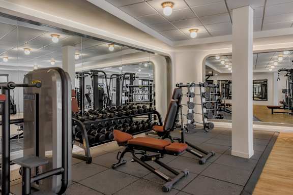 A gym with a variety of equipment including weights and machines.