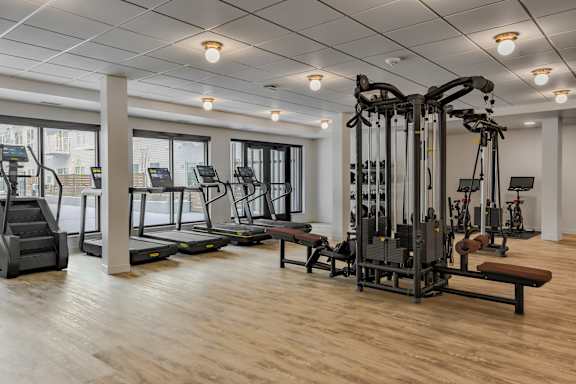 A gym with a variety of equipment including treadmills, weights, and benches.