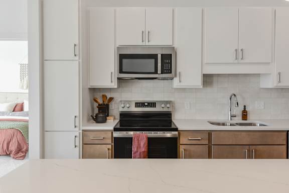 A kitchen with a stove, oven, microwave, and cabinets.