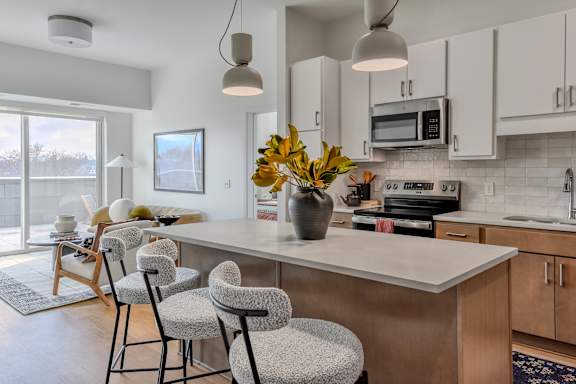 A kitchen with a white countertop and a vase of yellow flowers on it.