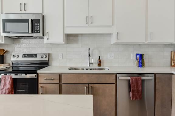 A kitchen with a white tile backsplash and wooden cabinets.