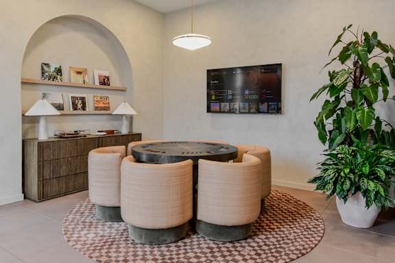 A room with a large table and a potted plant.