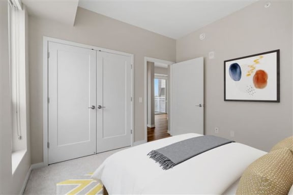 a white bedroom with a bed and a painting on the wall