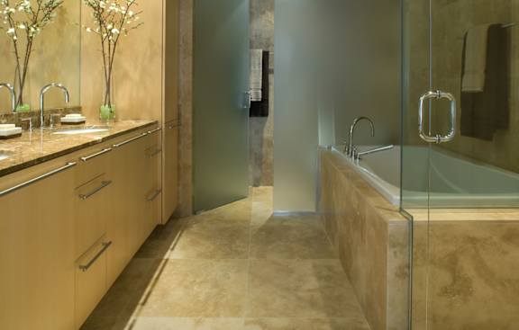 A bathroom with a glass shower stall and a sink with a mirror above it.