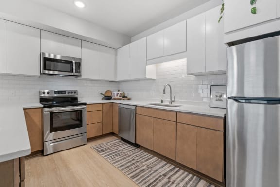 a modern kitchen with stainless steel appliances and white cabinets at The Aurilla, Cottage Grove, 55016