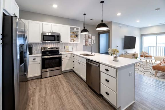 a large white kitchen with a stove and a sink at The Commons at Rivertown, Grandville, MI, 49418
