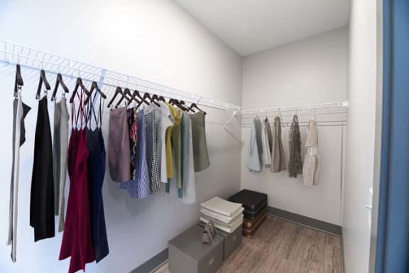 a closet with clothes hanging on a rack in a room at The Commons at Rivertown, Grandville, Michigan